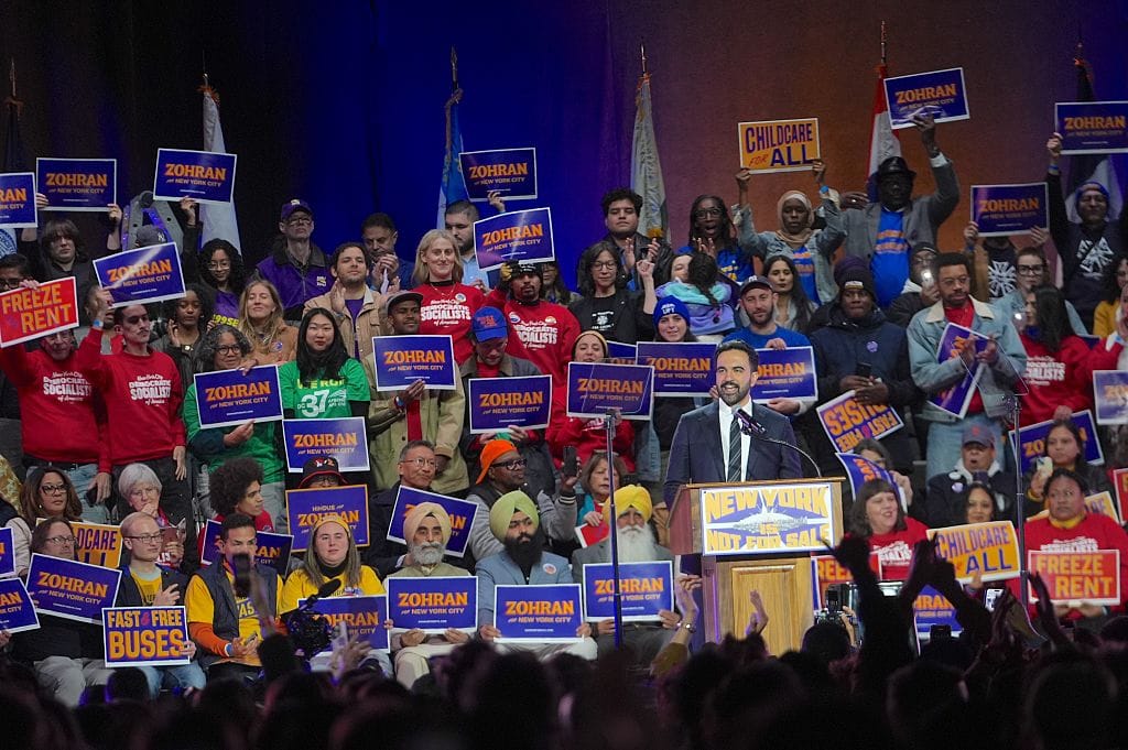 Mamdani at podium with supporters holding campaign signs. Photo: Selcuk Acar / Anadolu via Getty Images