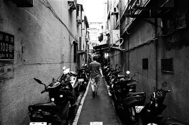 A man walking down a narrow alley in Taiwan